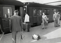 169781 Afbeelding van een kruier van de N.S. die bagage plaatst in een internationale trein langs het perron van het ...